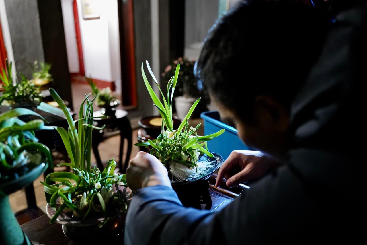 Một th&agrave;nh vi&ecirc;n của Nh&oacute;m Tinh hoa Thủy Ti&ecirc;n Việt đang nắn n&oacute;t chỉnh lại b&aacute;t hoa trước sự kiện ng&agrave;y mai.