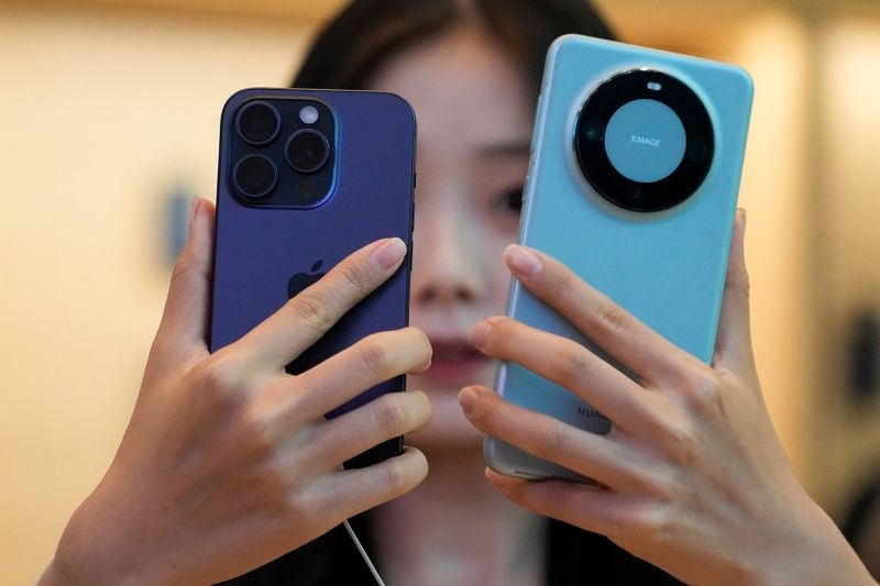 Một kh&aacute;ch h&agrave;ng Trung Quốc đang c&acirc;n nhắc giữa iPhone 15 Pro v&agrave; Huawei Mate 60 Pro.
