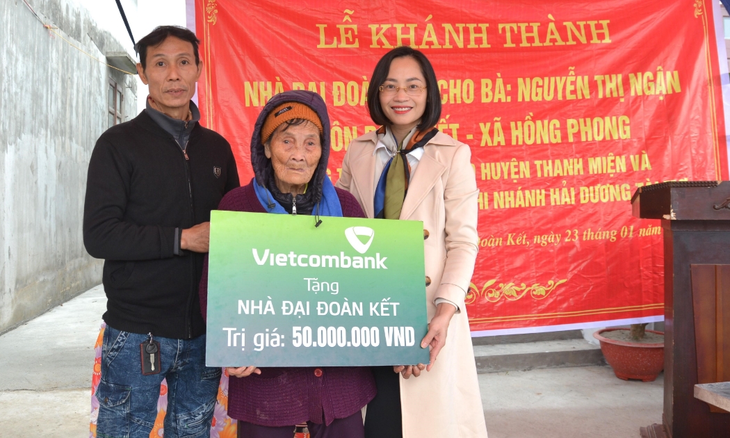 Bà Phạm Minh Đào - Phó Giám đốc Vietcombank Hải Dương (ngoài cùng bên phải) trao biển tặng nhà đại đoàn kết cho gia đình bà Nguyễn Thị Ngận, hộ nghèo thuộc huyện Thanh Miện, tỉnh Hải Dương.