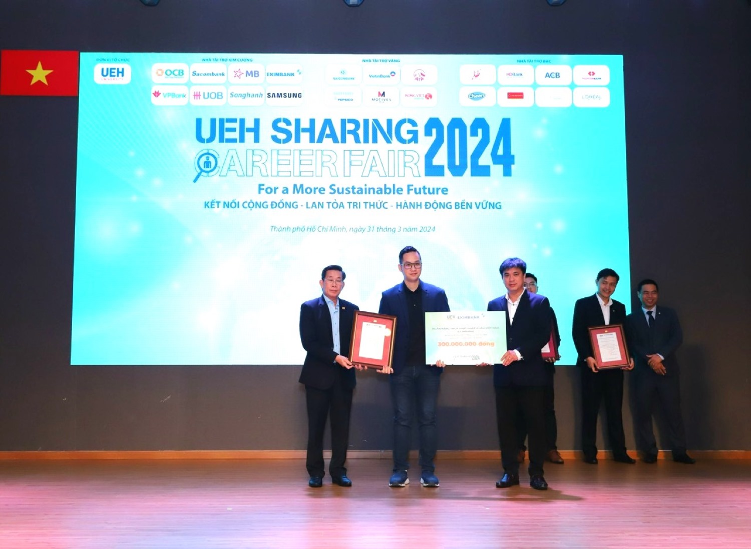 Đại diện Eximbank, ông Lương Nguyễn Minh Đăng (ở giữa) - Giám đốc Khối Khách hàng Cá nhân trao bảng tượng trưng tài trợ học bổng cho GS.TS. Sử Đình Thành - Giám đốc UEH (bên trái) và PGS.TS. Bùi Quang Hùng - Phó Giám đốc UEH.