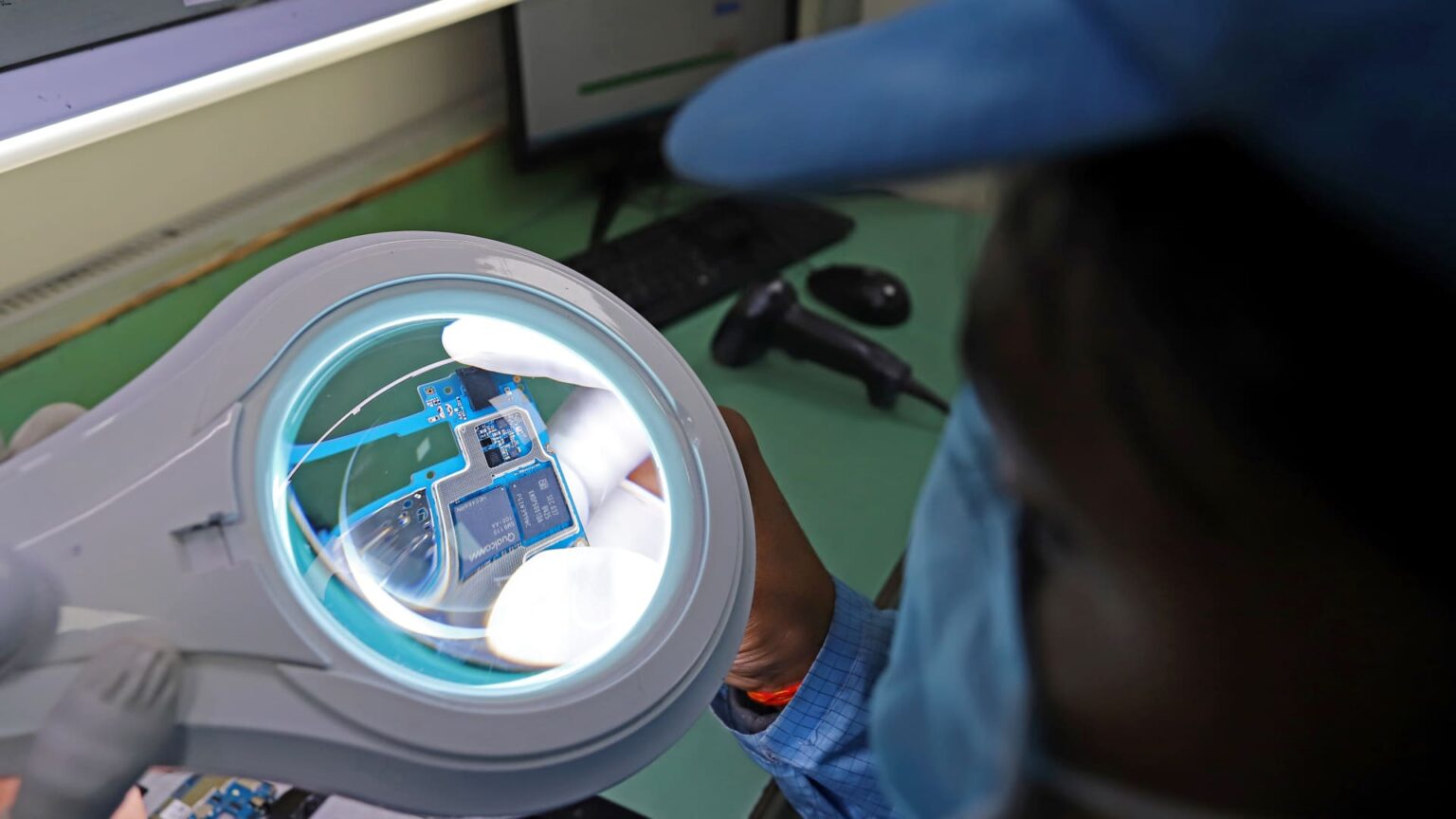 Một công nhân kiểm tra bảng mạch cho điện thoại thông minh tại nhà máy Padget Electronics Pvt của Dixon Technologies ở Noida, Uttar Pradesh, Ấn Độ