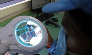 Một công nhân kiểm tra bảng mạch cho điện thoại thông minh tại nhà máy Padget Electronics Pvt của Dixon Technologies ở Noida, Uttar Pradesh, Ấn Độ