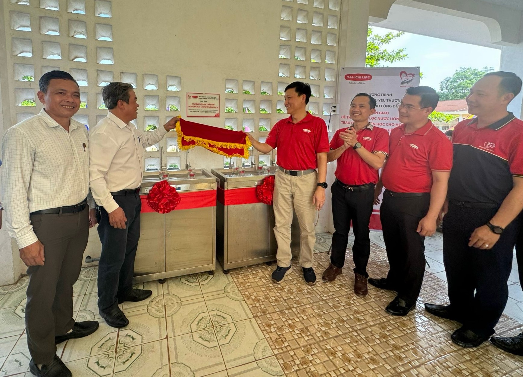 Ông Trần Đình Quân - Chủ tịch Hội đồng Thành viên Dai-ichi Life Việt Nam kiêm Chủ tịch Quỹ Vì cuộc sống tươi đẹp (thứ tư, từ phải qua) thực hiện nghi thức bàn giao hai hệ thống máy lọc nước uống sạch cho trường Tiểu học Thiết Sơn, tỉnh Quảng Bình vào tháng 4/2024.