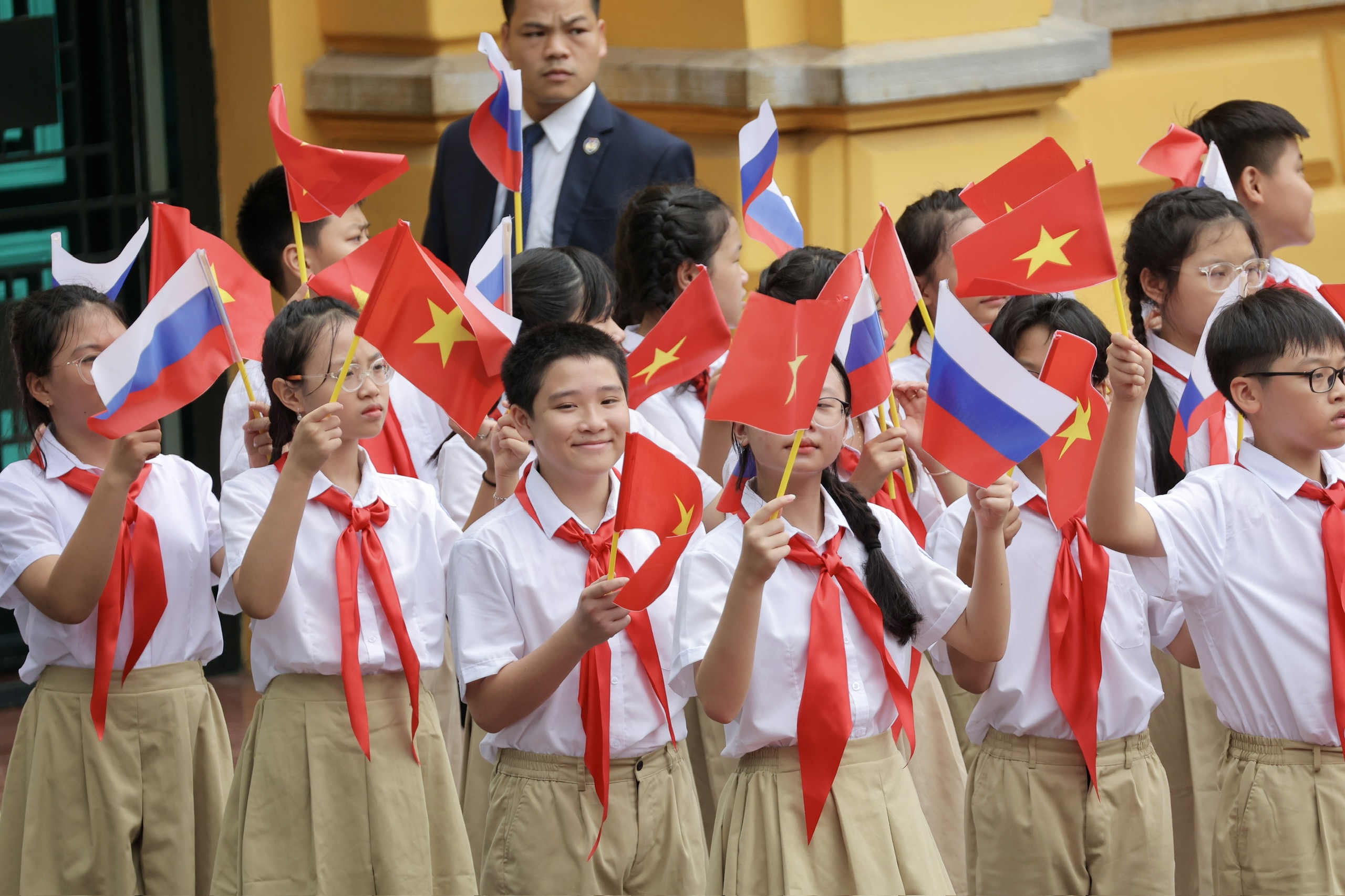 C&aacute;c em thiếu nhi trong Phủ Chủ tịch v&agrave; h&agrave;ng trăm thanh ni&ecirc;n cầm cờ Việt Nam v&agrave; Nga, đứng dọc hai b&ecirc;n đường ch&agrave;o đ&oacute;n Tổng thống Putin.
