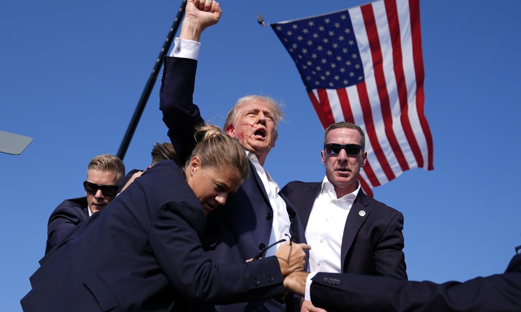 Cựu Tổng thống Mỹ Donald Trump được lực lượng Mật vụ bảo vệ sau khi bị bắn sượt qua tai hôm 13/7 - Ảnh: AP/Bloomberg.