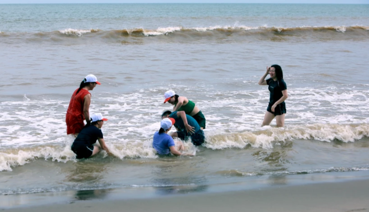 Nhóm du khách vô tư đùa nghịch trên biển dù các phương tiện báo đài truyền thông đưa tin về siêu bão Yagi.