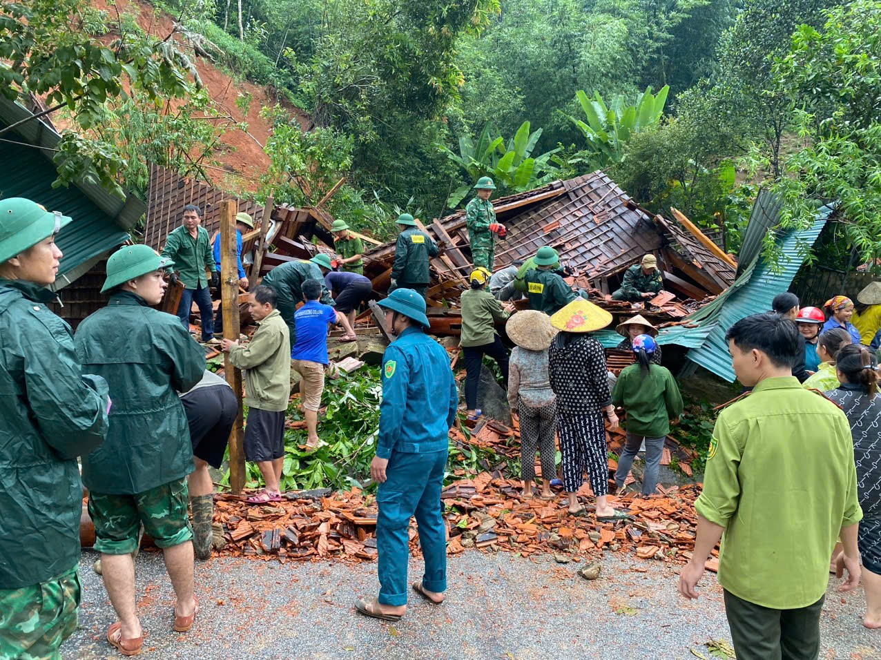 Các lực lượng chức năng xã Thông Thụ, huyện Quế Phong (Nghệ An) và người dân  giúp gia đình chị Lương Thị Hòa ở bản Mường Piệt tháo dỡ căn nhà bị sạt lở núi làm hư hỏng. Ảnh Văn Trường