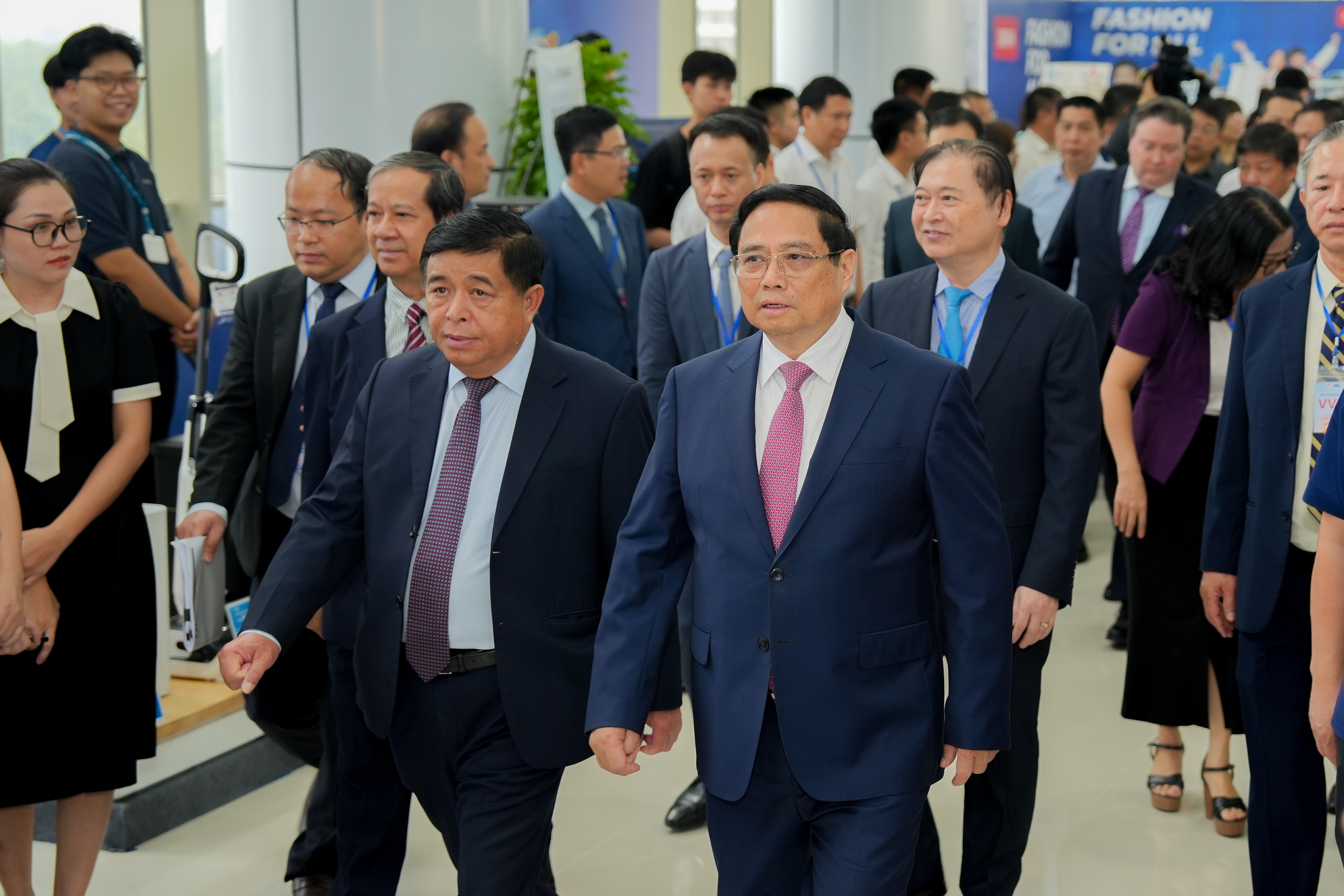 Thủ tướng Phạm Minh Chính và Bộ trưởng Bộ Kế hoạch và Đầu tư đi thăm các gian hàng trưng bày tại NIC trước khi dự Lễ kỷ niệm 5 năm thành lập NIC. Ảnh: MPI.
