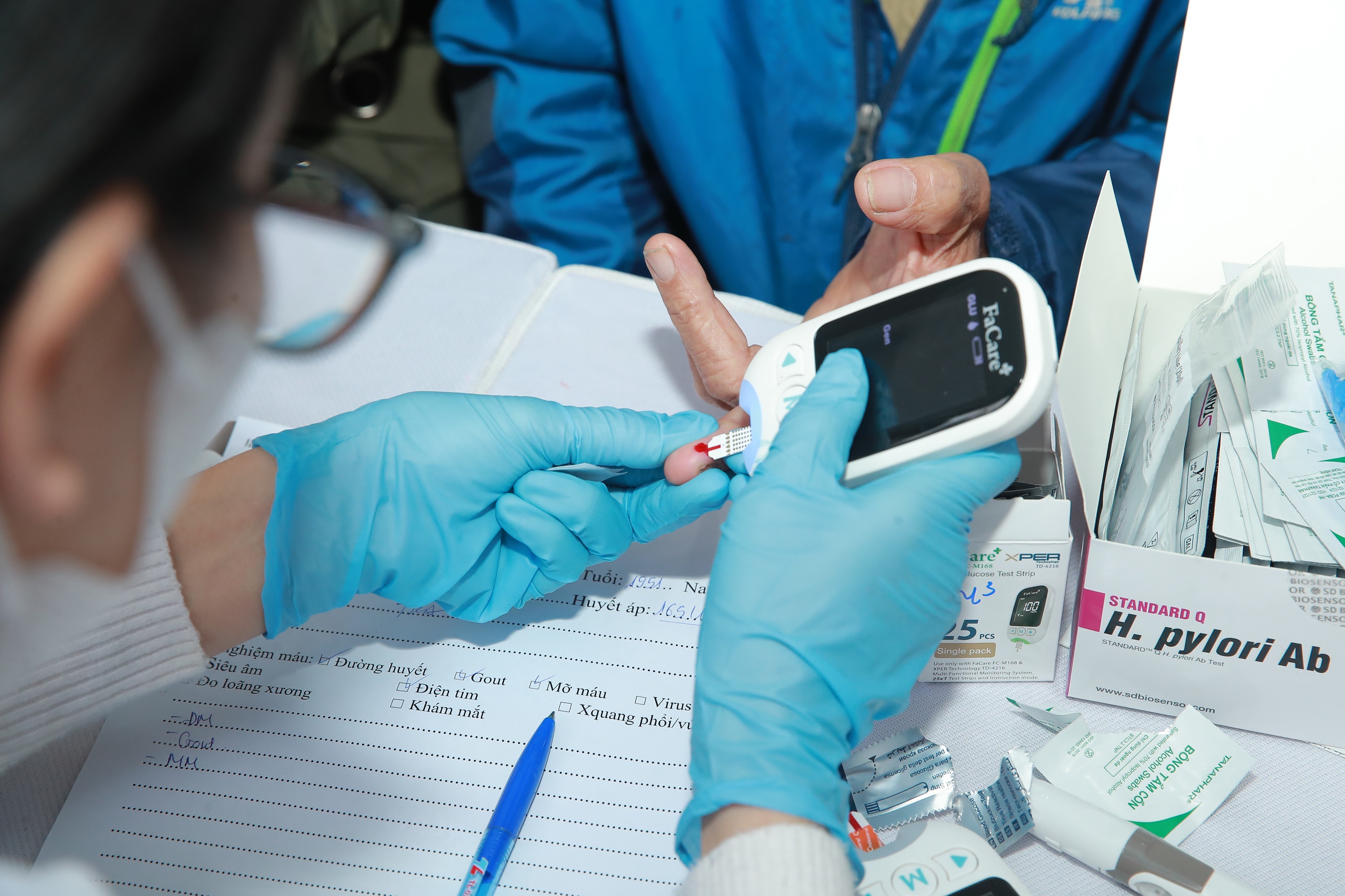 Cán bộ y tế lấy máu để tầm soát vi khuẩn HP cho người dân. Ảnh Hiền Trinh.