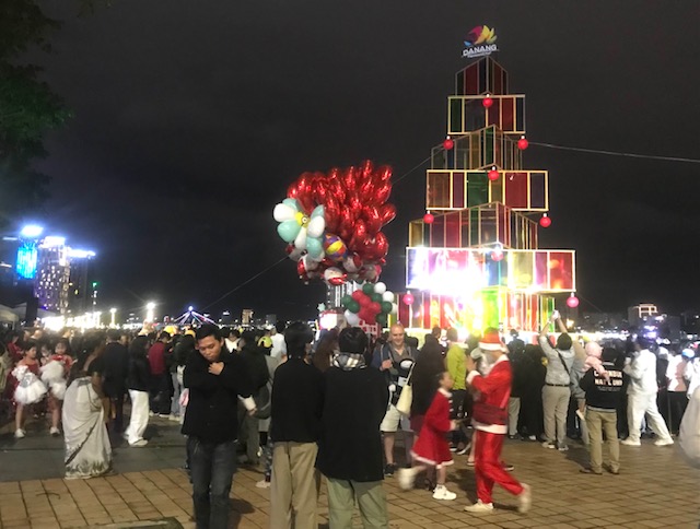 Ông già Noel tặng quà cho trẻ em dưới cây thông  bên bờ sông Hàn. Ảnh Ngô Anh Văn