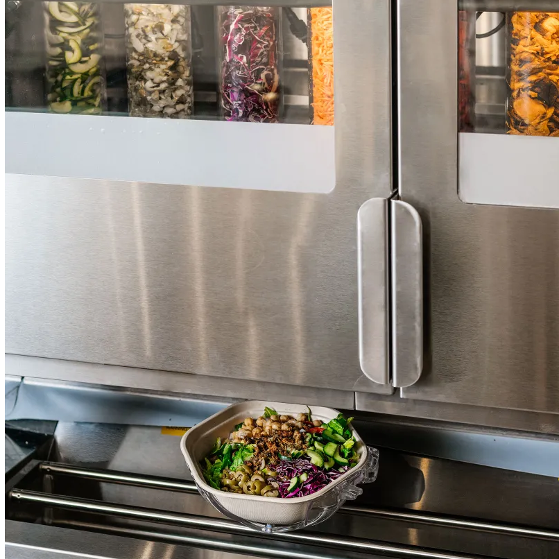 Robot Infinite Kitchen thực hiện trộn salad, rồi đưa món ăn chạy theo băng chuyền.