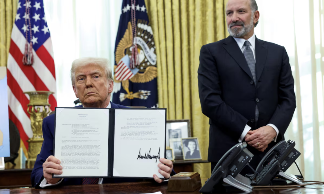 Tổng thống Mỹ Donald Trump ký một sắc lệnh thuế quan ở Nhà Trắng hôm 13/2. Đứng sau ông Trump là Bộ trưởng Bộ Thương mại Mỹ Howard Lutnick - Ảnh: Reuters.