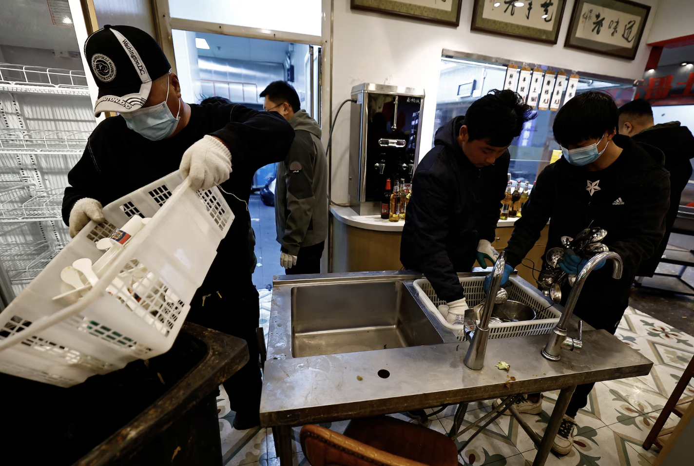 Nhân viên của An Dawei thu gom đồ đạc và thiết bị trong một nhà hàng phải đóng cửa ở Bắc Kinh hôm 22/2 - Ảnh: Reuters.