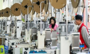 Công nhân xử lý cáp dữ liệu tại xưởng của một công ty điện tử ở khu phát triển kinh tế huyện Anlong, Trung Quốc. 