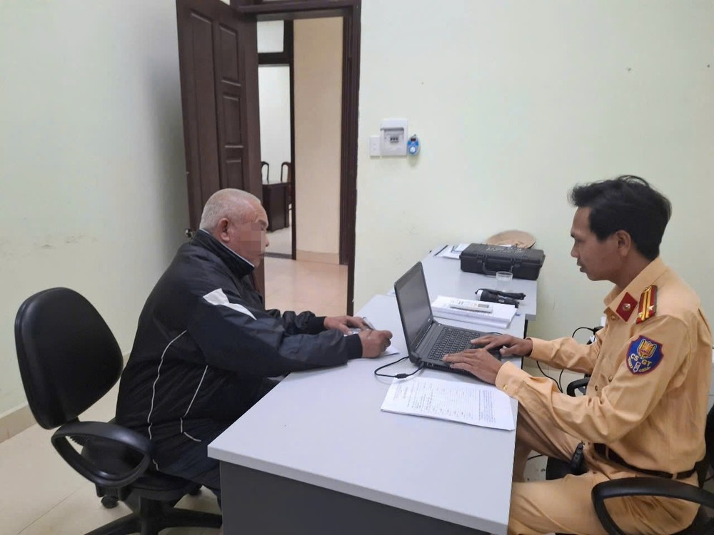 Cảnh sát giao thông lập biên bản xử phạt tài xế ô tô có hành vi cố tình vượt qua đường sắt khi tàu sắp đến. Ảnh: VNR.