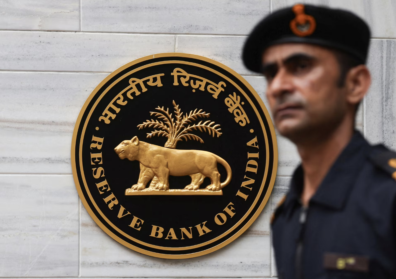 Một người đàn ông đi ngang qua logo của Ngân hàng Trung ương Ấn Độ (RBI) ở trụ sở của cơ quan này ở Mumbai, ngày 6/6/2025 - Ảnh: Reuters.