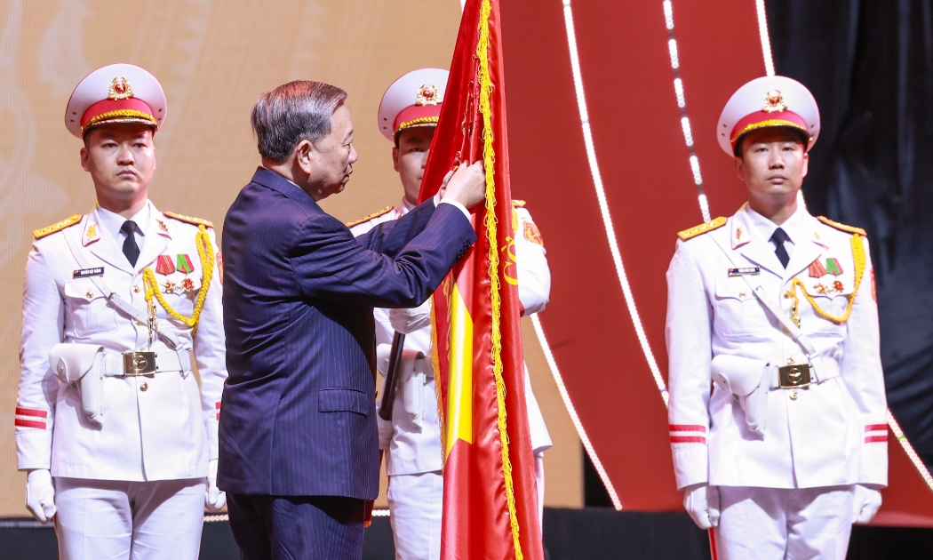 Tổng Bí thư Tô Lâm gắn Huân chương Hồ Chí Minh lên lá cờ truyền thống của Báo chí cách mạng Việt Nam. Ảnh: Trí Phong.