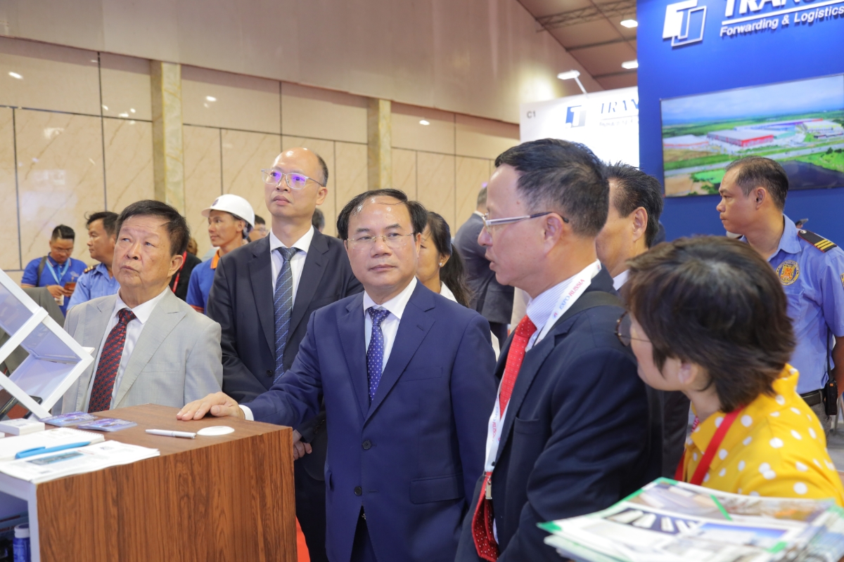 Thứ trưởng Bộ Xây dựng Nguyễn Văn Sinh (áo xanh, đứng ở giữa) cùng các đại biểu tham quan gian hàng tại triển lãm.