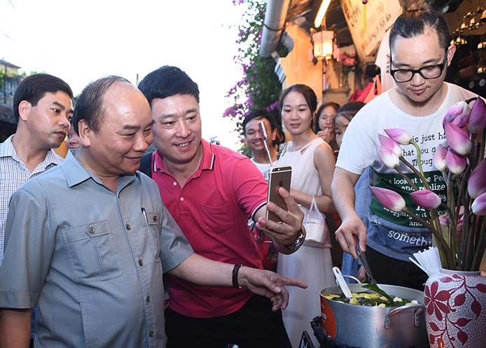 Thủ tướng Nguyễn Xuân Phúc chụp ảnh cùng du khách tại Hội An, chiều 8/8 - Ảnh: VGP.<br>