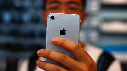 Một khách hàng xem chiếc điện thoại iPhone mới mua trong một cửa hiệu Apple Store ở Bắc Kinh, Trung Quốc - Ảnh: Reuters/CNBC.