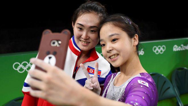 Hai nữ vận động viên thể dục dụng cụ của Triều Tiên (trái) và Hàn Quốc (phải) cùng chụp ảnh tự sướng ở Thế vận hội Rio - Ảnh: Reuters/BBC.<br>