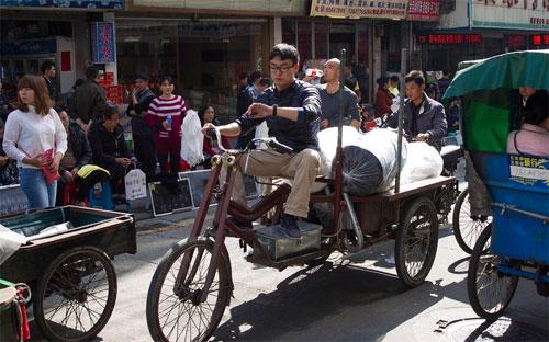 Một người giao hàng lái xe 3 bánh trên đường phố ở Quảng Châu, Trung Quốc - Ảnh: Bloomberg/Getty.<br>