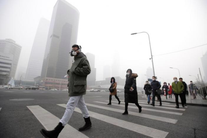 Người đi bộ đeo khẩu trang để tránh ô nhiễm ở quận tài chính trung tâm thủ đô Bắc Kinh của Trung Quốc ngày 21/12 - Ảnh: Reuters.<br>