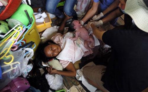 Một phụ nữ ở Tacloban, Philippines sinh con trên đống đổ nát của thành phố này sau siêu bão lịch sử Haiyan - Ảnh: EPA.<br>
