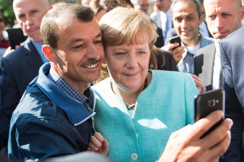 Thủ tướng Đức Angela Merkel chụp ảnh selfie cùng một người di cư hồi tháng 10/2015 tại Berlin - Ảnh: EPA/WSJ.<br>