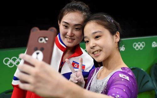 Hai nữ vận động viên thể dục dụng cụ của Triều Tiên (trái) và Hàn Quốc 
(phải) cùng chụp ảnh tự sướng ở Thế vận hội Rio 2016 - Ảnh: Reuters/BBC.