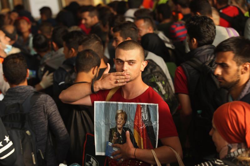 Một người di cư mang theo ảnh của Thủ tướng Đức Angela Merkel khi vào Đức hồi năm 2015 - Ảnh: Getty.<br>