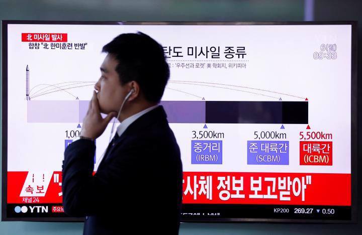Một người đàn ông đi qua màn hình TV đang phát bản tin về vụ phóng tên lửa sáng 6/3 của Triều Tiên. Ảnh chụp tại một nhà ga ở Seoul, Hàn Quốc sáng 6/3 - Ảnh: Reuters.<br>