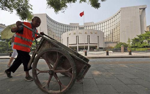 Một người công nhân đẩy xe qua trụ sở Ngân hàng Trung ương Trung Quốc (PBoC) ở Bắc Kinh - Ảnh: EPA/WSJ.<br>