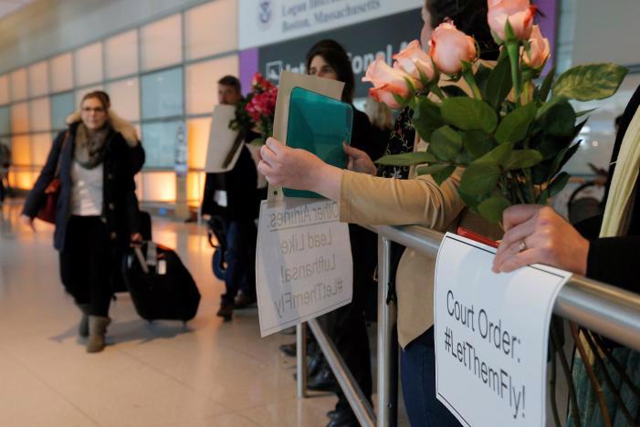 Người phản đối lệnh cấm nhập cảnh của Tổng thống Donald Trump giơ khẩu hiệu khi đón hành khách quốc tế ở sân bay Logan, Boston, Mỹ, ngày 3/2 - Ảnh: Reuters.<br>