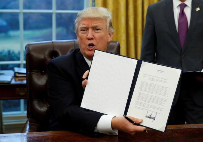 Tổng thống Mỹ Donald Trump và sắc lệnh được ông ký ngày 23/1 về rút Mỹ khỏi TPP - Ảnh: Reuters.<br>