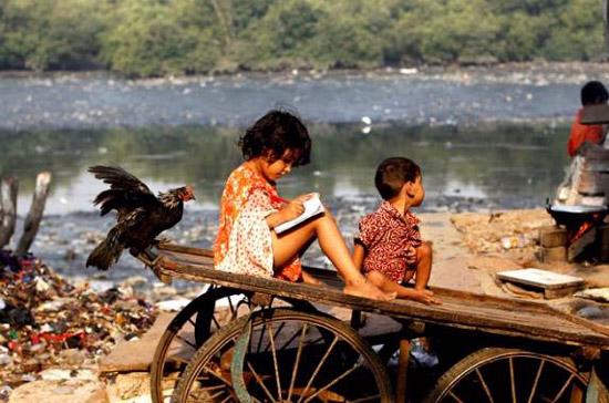  Bé gái Ấn Độ ở một khu ổ chuột tại thành phố Mumbai đang chăm chú tập viết - Ảnh: AP.