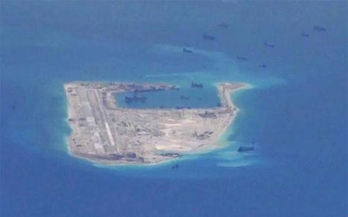 Tàu nạo vét của Trung Quốc hoạt động quanh đá Chữ Thập thuộc quần đảo Trường Sa của Việt Nam. Ảnh cắt từ một đoạn video quay từ máy bay trinh sát P-8A Poseidon do Hải quân Mỹ cung cấp ngày 21/5/2015 - Nguồn: Reuters.<br>