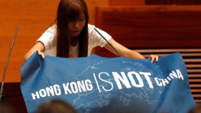 Một nghị sỹ Hồng Kông giơ biểu ngữ phản đối Trung Quốc tại lễ tuyên thệ ngày 12/10 - Ảnh: Reuters/BBC.<br>