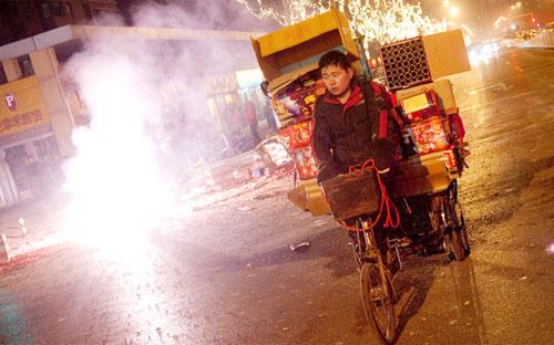 Một người đàn ông đi thu lượm những hộp đựng pháo hoa trong dịp Tết Nguyên đán ở Bắc Kinh, Trung Quốc hồi năm 2011 - Ảnh: New York Times.<br>