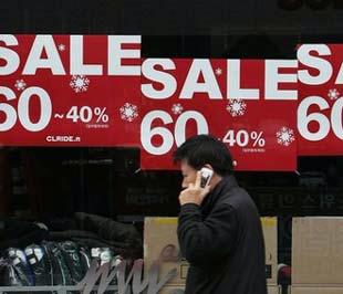 Một người đàn ông đi ngang qua dãy biển quảng cáo giảm giá tại Seoul, thủ đô Hàn Quốc. Kinh tế nước này đang trong giai đoạn nhiều thử thách - Ảnh: Reuters.