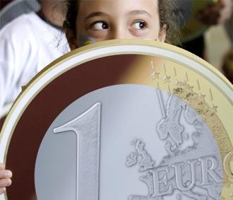 Một em bé ở Brussels (Bỉ) đang cầm một mô hình của đồng xu 1 Euro - Ảnh: Reuters.