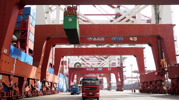 Xe tải chở những container hàng hóa tại cảng biển ở Thanh Đảo, Trung Quốc - Ảnh: Reuters.