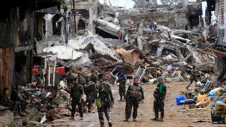 Các binh sỹ chính phủ Philippines đứng trước một khu nhà bị phá hủy hoàn toàn ở Marawi, tháng 10/2017 - Ảnh: Reuters.
