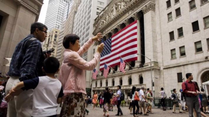 Một du khách Trung Quốc đang chụp ảnh bên ngoài Sở giao dịch chứng khoán New York (NYSE) ở New York, Mỹ - Ảnh: Reuters.