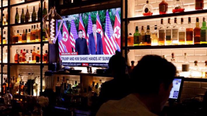 Màn hình TV phát sóng bản tin về cuộc gặp thượng đỉnh Mỹ-Triều trong một quán bar ở Manhattan, New York hôm 12/6 - Ảnh: Reuters.