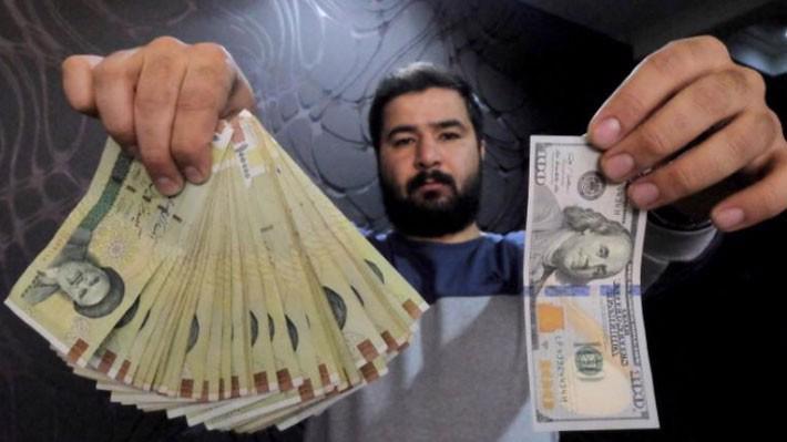 Một nhà đổi tiền ở thủ đô Tehran của Iran trưng tờ 100 USD (phải) và số tiền tương ứng bằng đồng Rial hôm 20/1/2016 - Ảnh: Reuters.