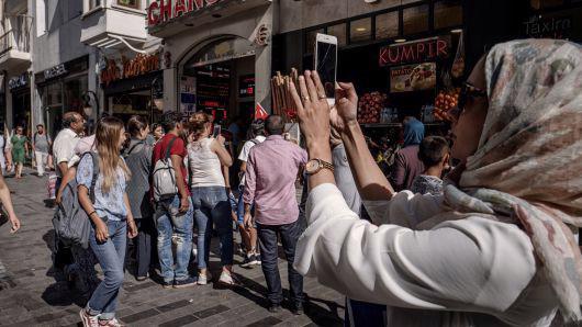 Một phụ nữ dùng điện thoại iPhone để chụp hình trên đường phố ở Istanbul, Thổ Nhĩ Kỳ ngày 13/8 - Ảnh: Bloomberg/CNBC.