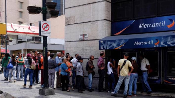Người Venezuela xếp hàng chờ rút tiền trước một cây ATM ở Caracas ngày 17/8 - Ảnh: Reuters.