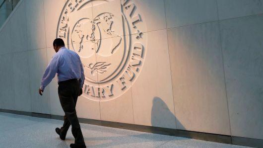 Một người đàn ông đi ngang qua logo của Quỹ Tiền tệ Quốc tế (IMF) bên ngoài trụ sở của định chế này ở Washington DC, Mỹ - Ảnh: Reuters.