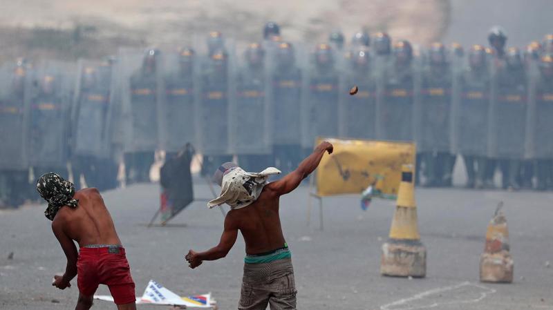 Người biểu tình ném gạch đá về phía lực lượng vệ binh quốc gia Venezuela ở biên giới giữa nước này với Brazil hôm 24/2 - Ảnh: Reuters.